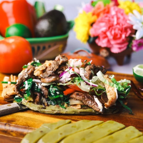 Amanecer Cocina y Cafe's carne asada sope with fresh vegetables and flowers in the background.